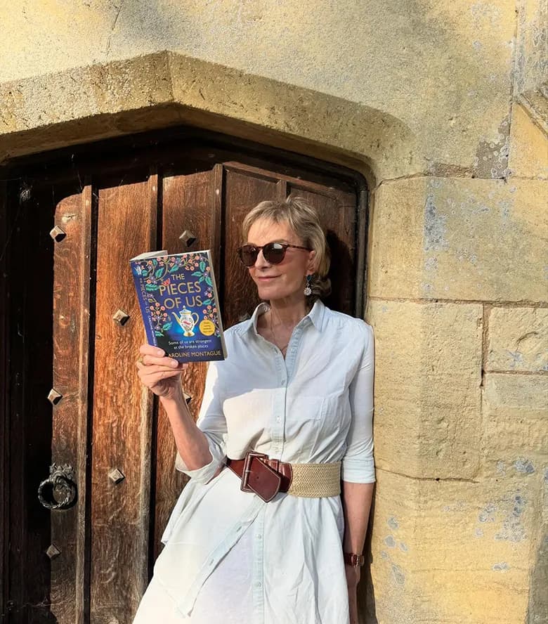 Caroline Montague holding The Pieces of Us outside a stone building