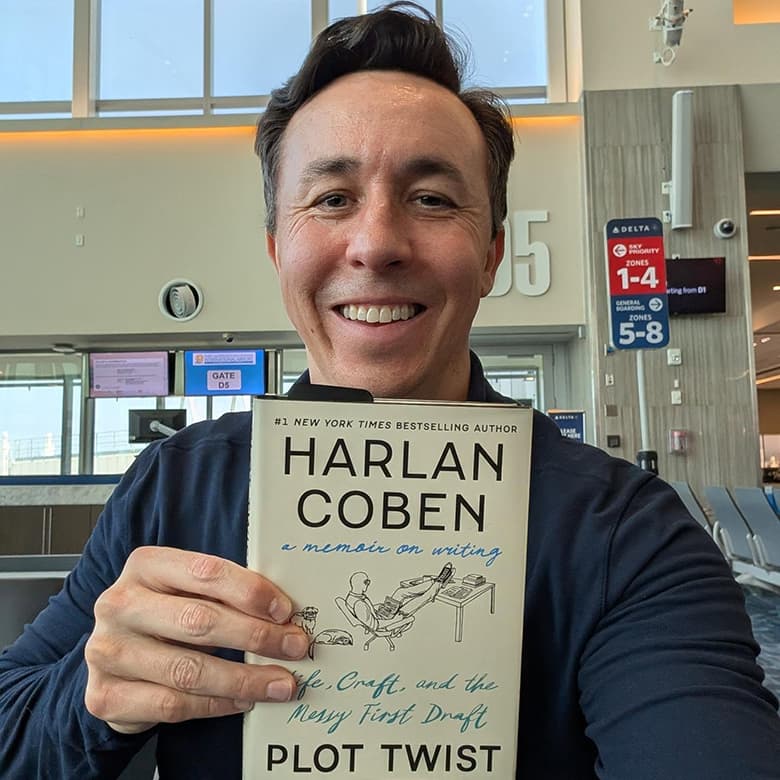 Daniel G. Miller smiling and holding Harlan Coben's Plot Twist book
